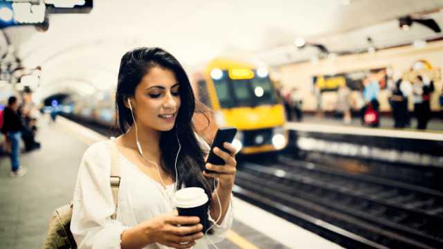 Woman in foreground on phone at Train Station